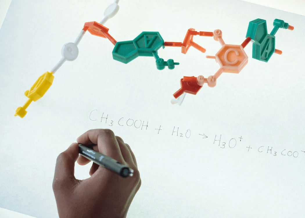 Person holding a black pen writing a chemical equation