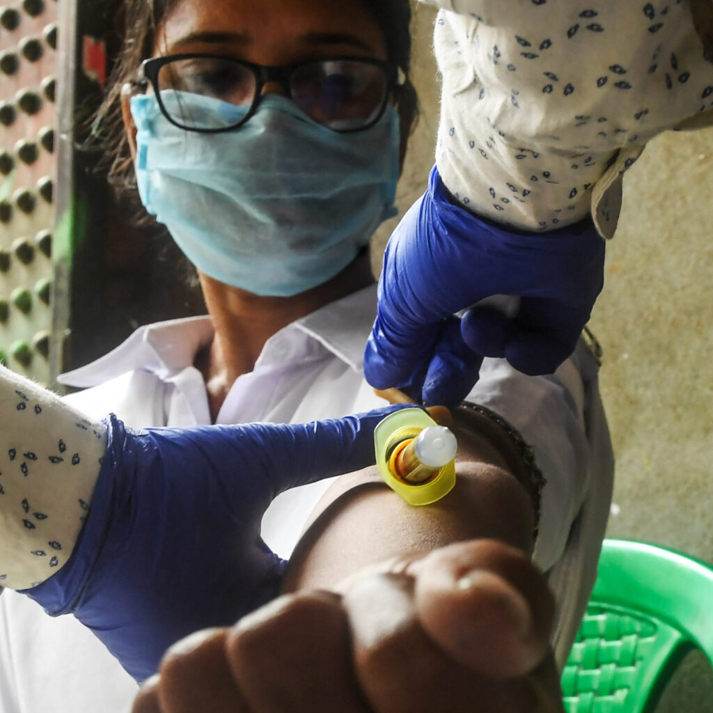 A health worker collects a blood sample from a police official for antibodies test of COVID-19 coronavirus, in Kolkata on August 23, 2020. (Photo by Dibyangshu SARKAR / AFP)